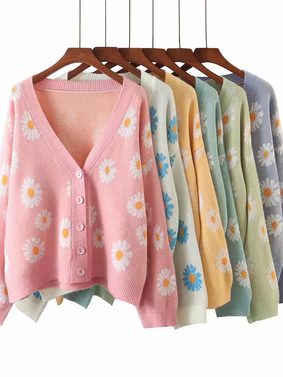 6 cardigans à fleurs de marguerite de couleurs différentes suspendus à des cintres.