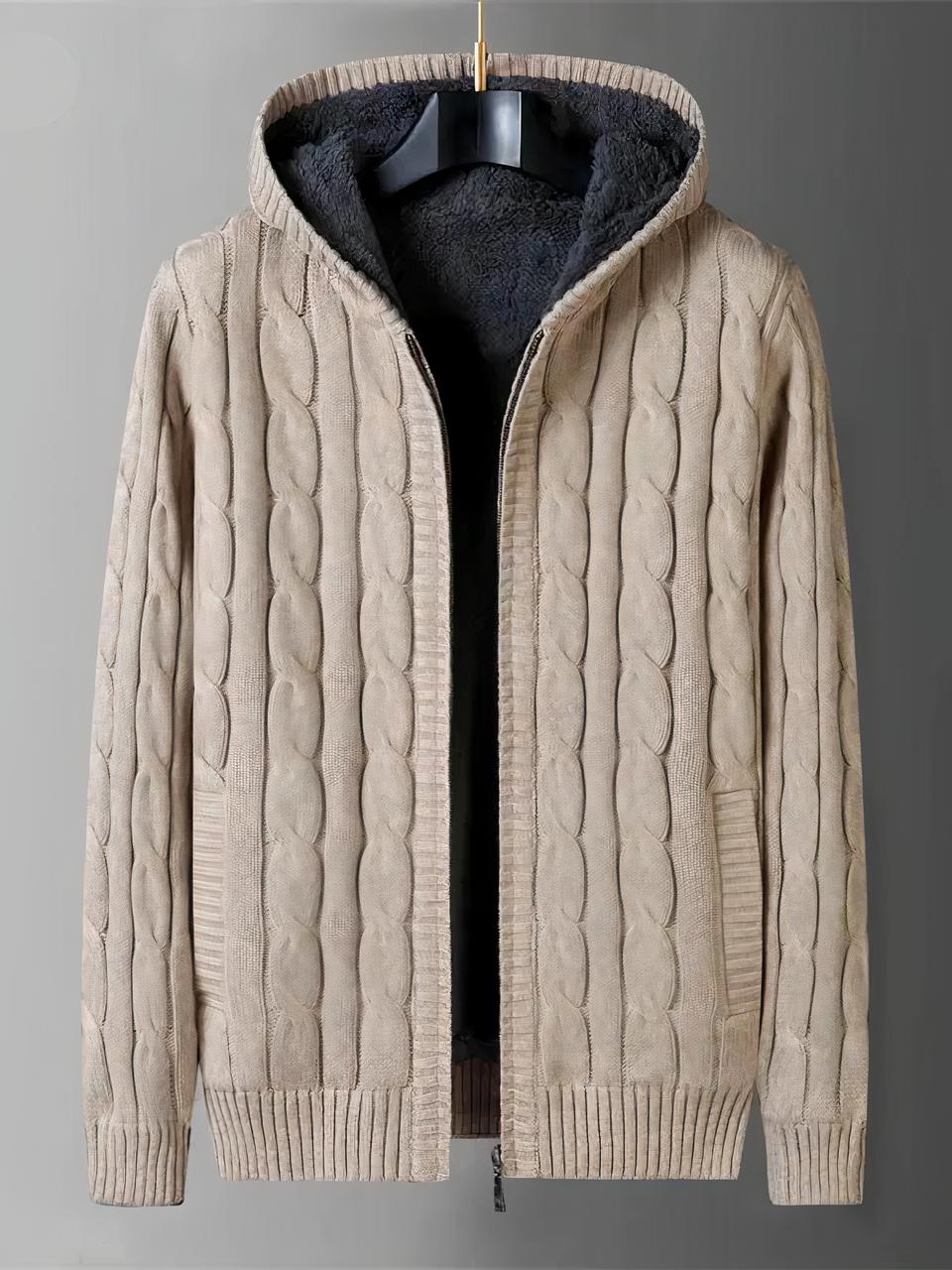 Cardigan capuche homme entièrement réversible Photo d'un cardigan homme à capuche en tricot beige torsadé, zippé et entièrement doublé de polaire, sur un cintre en bois marron foncé, le tout sur un fond gris clair à gauche et gris foncé à droite