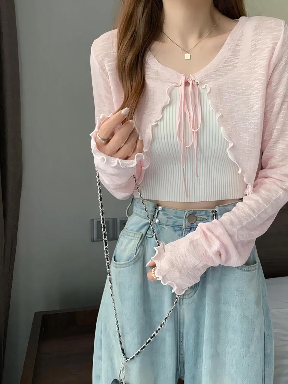 Une femme brune porte un jean, un top blanc et un gilet court rose fermé par un lacet