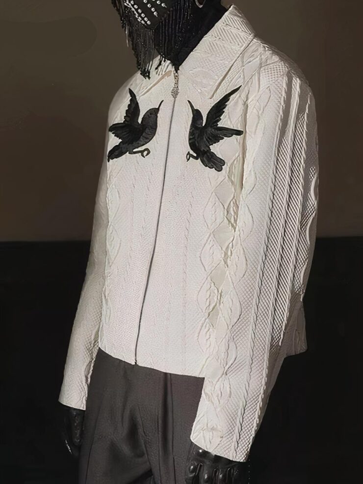 Un cardigan zippé blanc avec 2 oiseaux noirs et un motif jacquard blanc. Porté avec un pantalon noir