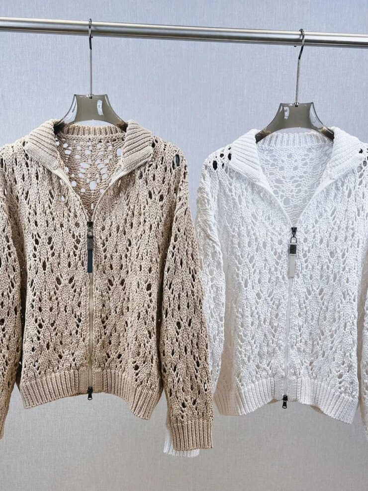 Photo représentant deux cardigans chic et originaux faits au crochet, accrochés sur cintres sur une barre, l'un blanc et l'autre beige, sur un fond gris clair