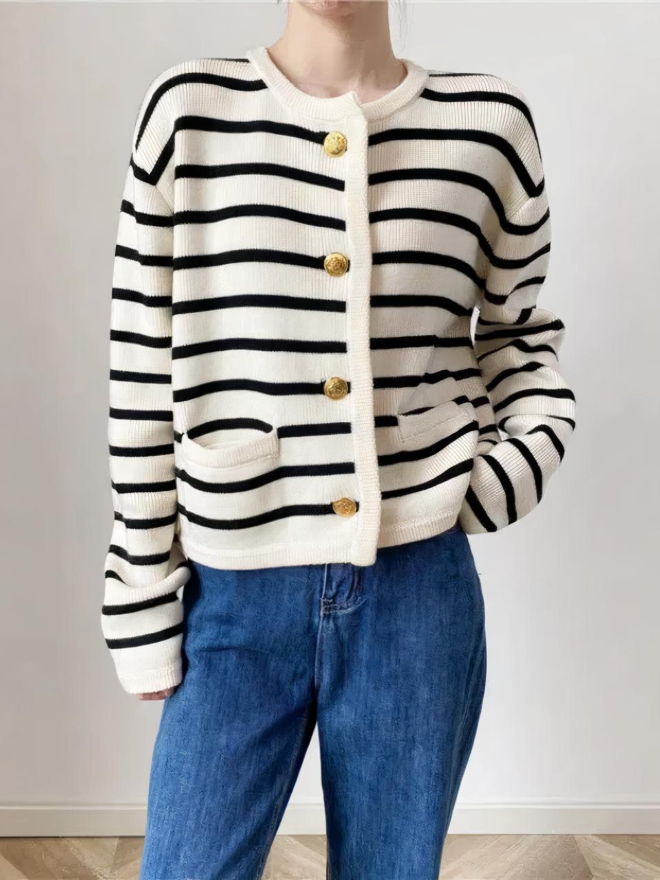 Cardigan rauyé blanc et bleu avec des boutons dorés porté par une femme portant un jean