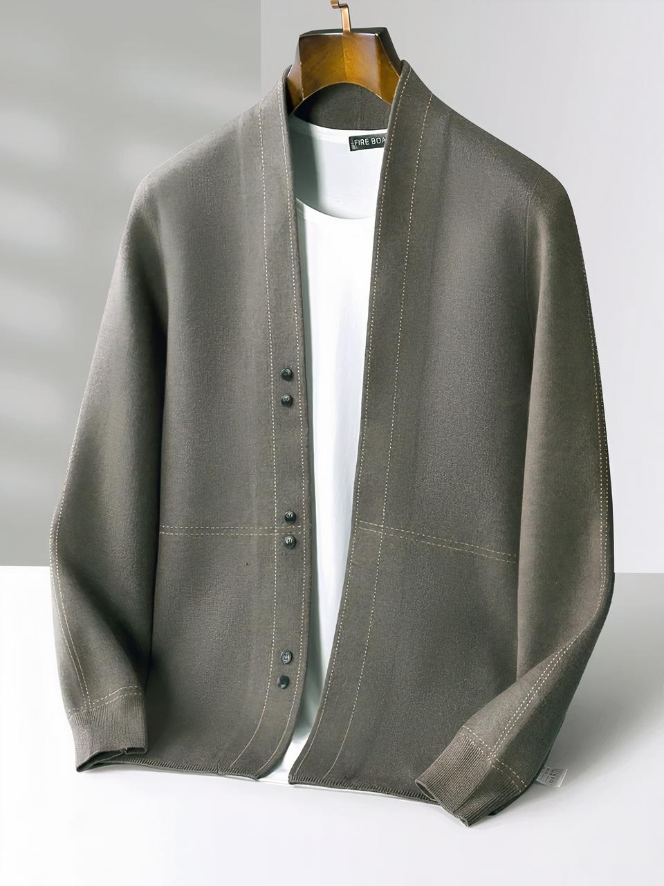 Photo d'une veste cardigan pour homme gris-vert à surpiqures en laine mérinos sur un top blanc, les deux sur un cintre marron foncé en bois sur un fond blanc et gris clair