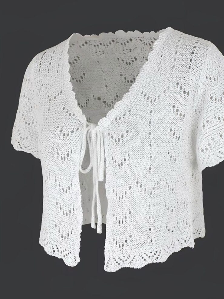 Cardigan à manches courtes blanc sur fond gris.