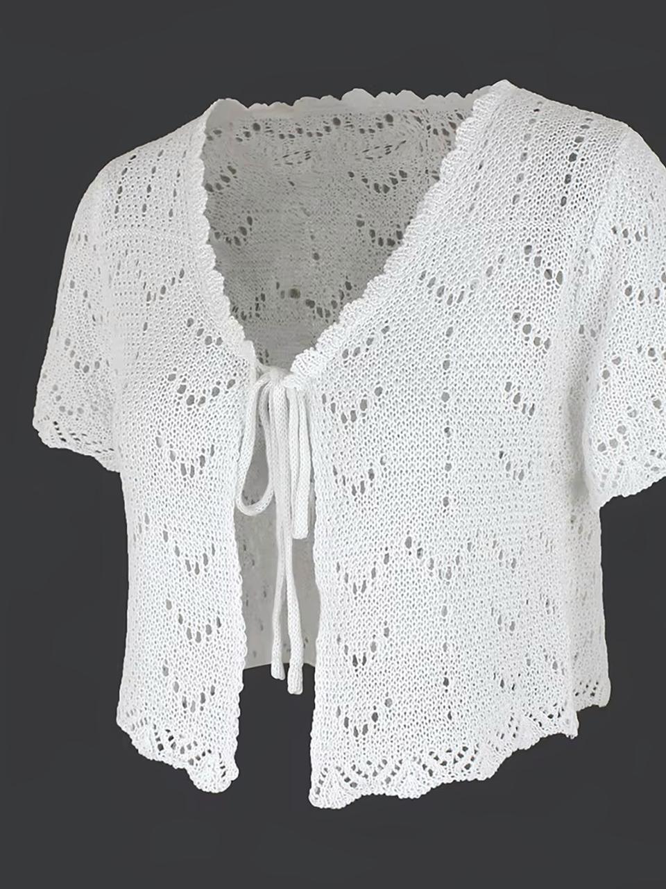 Cardigan à manches courtes blanc sur fond gris.