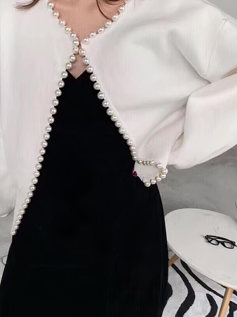Femme portant un cardigan blanc avec des perles.